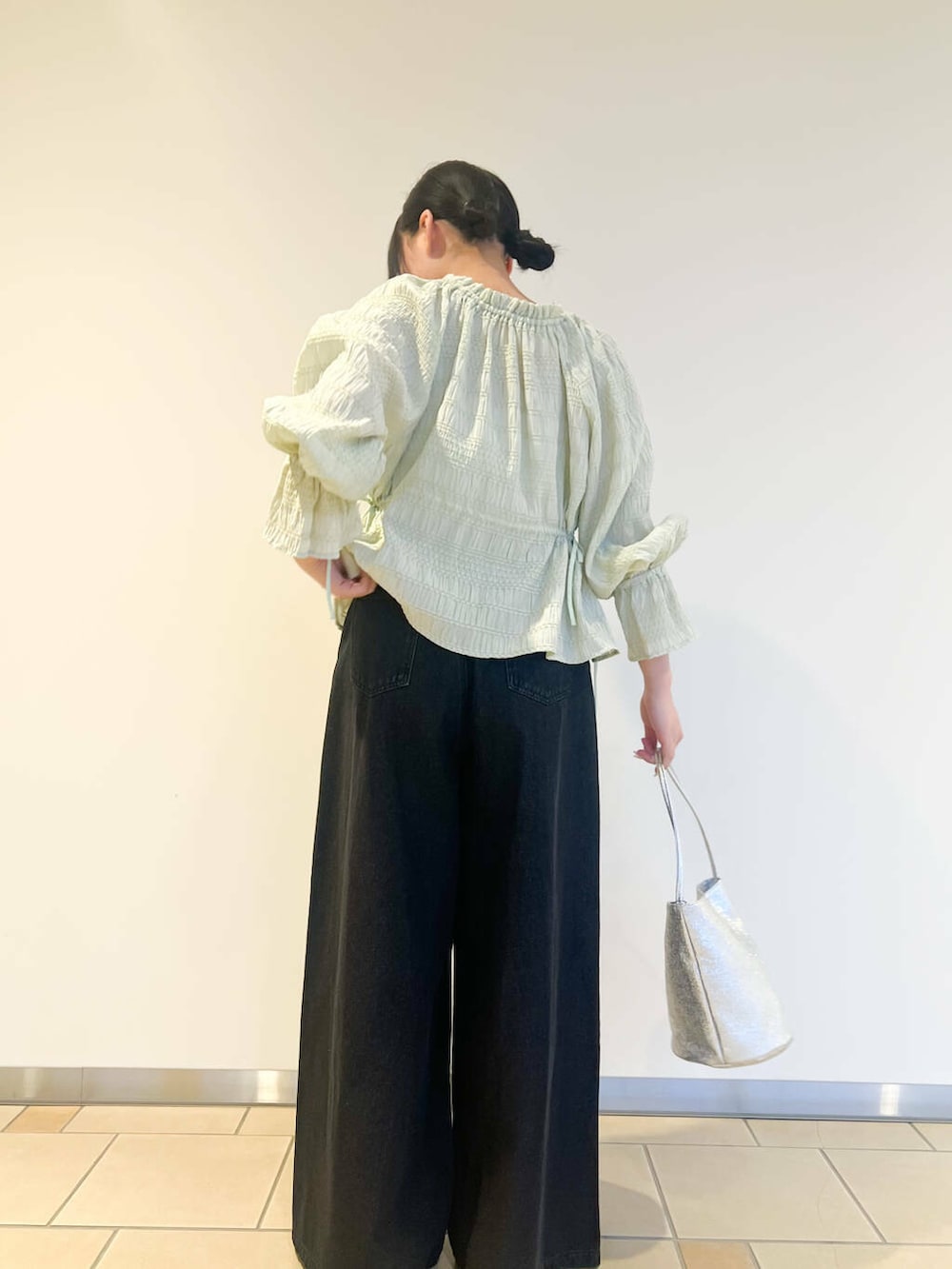 シルバー系のハンドバッグ、ブラック系のデニムパンツ、グリーン系のシャツ/ブラウスを着用したレディースの春コーディネートの3枚目の写真