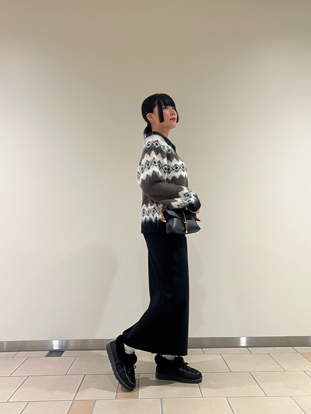 ブラウン系のカーディガン/ボレロ、ブラック系のスカート、ブラック系のショルダーバッグを着用したレディースの冬コーディネートの2枚目の写真