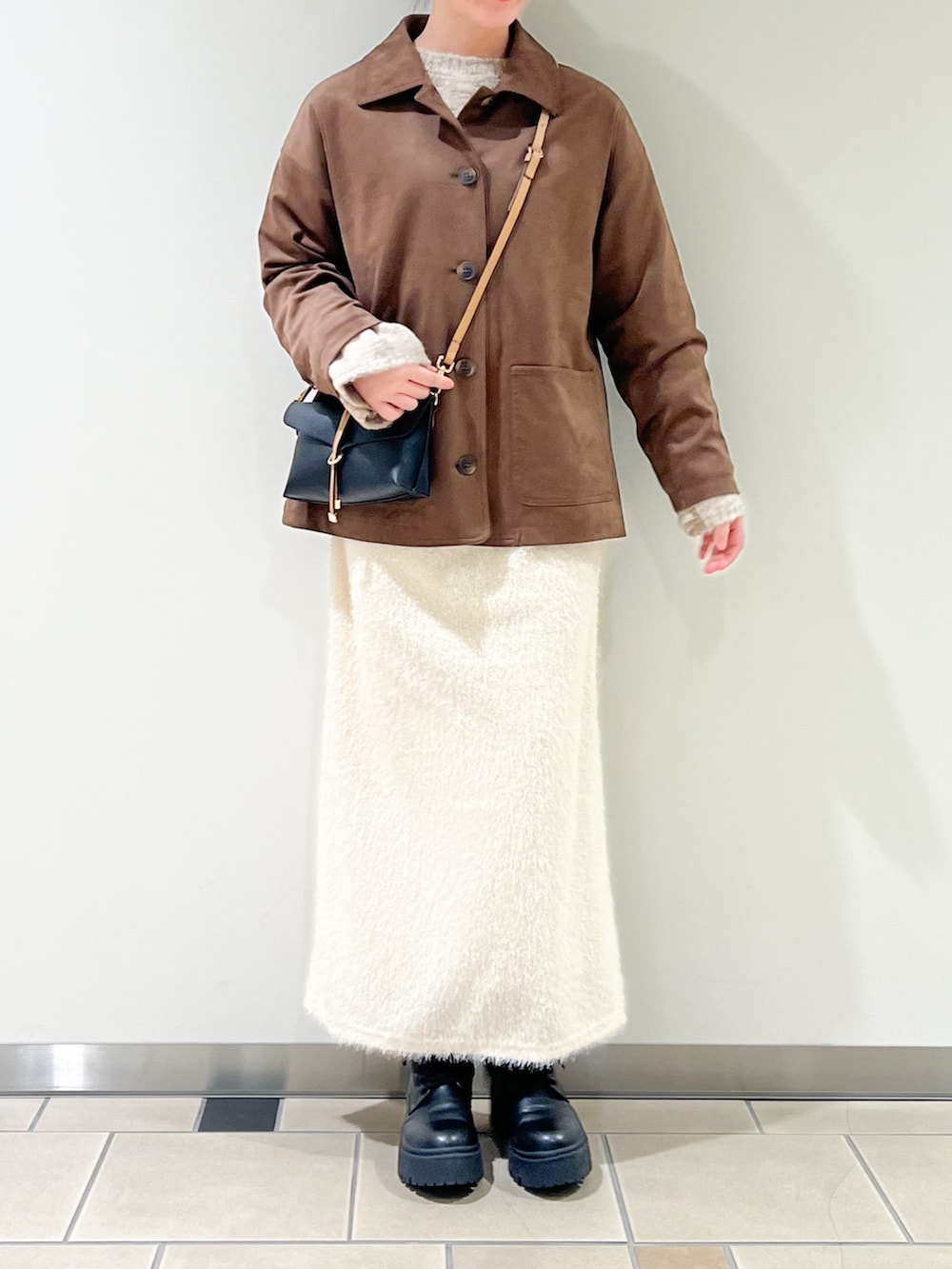 ベージュ系のニット/セーター、ブラウン系のその他アウター、ホワイト系のスカートを着用したレディースの冬コーディネートの2枚目の写真