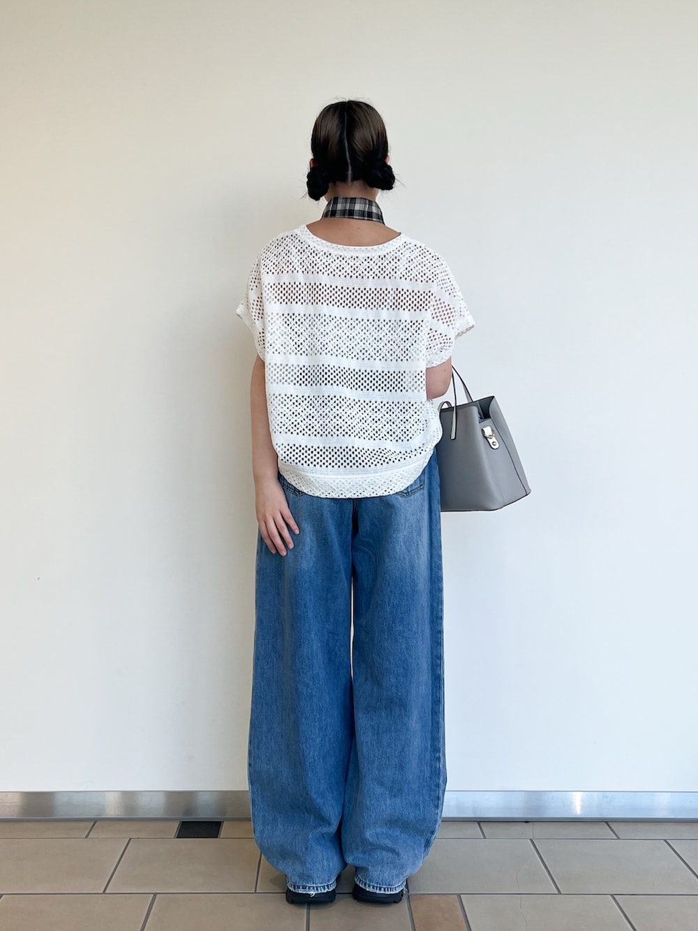 グレー系のハンドバッグ、ブルー系のデニムパンツ、ホワイト系のその他トップスを着用したレディースの夏コーディネートの3枚目の写真