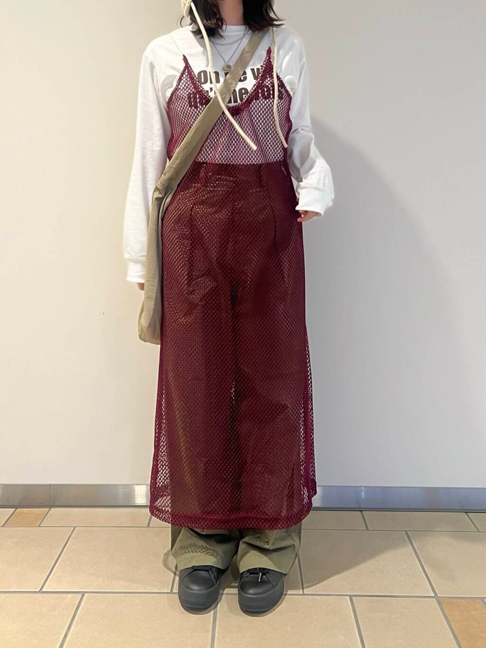 ベージュ系のショルダーバッグ、レッド系のワンピース、グリーン系のチノパンツを着用したレディースの秋コーディネートの3枚目の写真