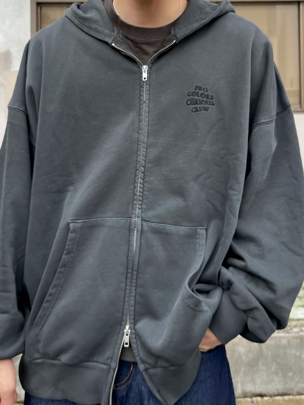 グレー系のパーカー、ブルー系のデニムパンツ、ブラック系のローファーを着用したメンズの秋コーディネートの3枚目の写真