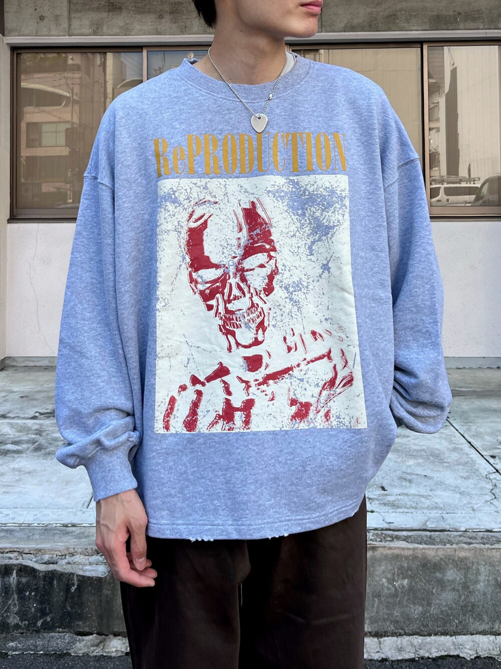 グレー系のスウェット、ブラウン系のデニムパンツ、グレー系のスニーカーを着用したメンズの秋コーディネートの3枚目の写真