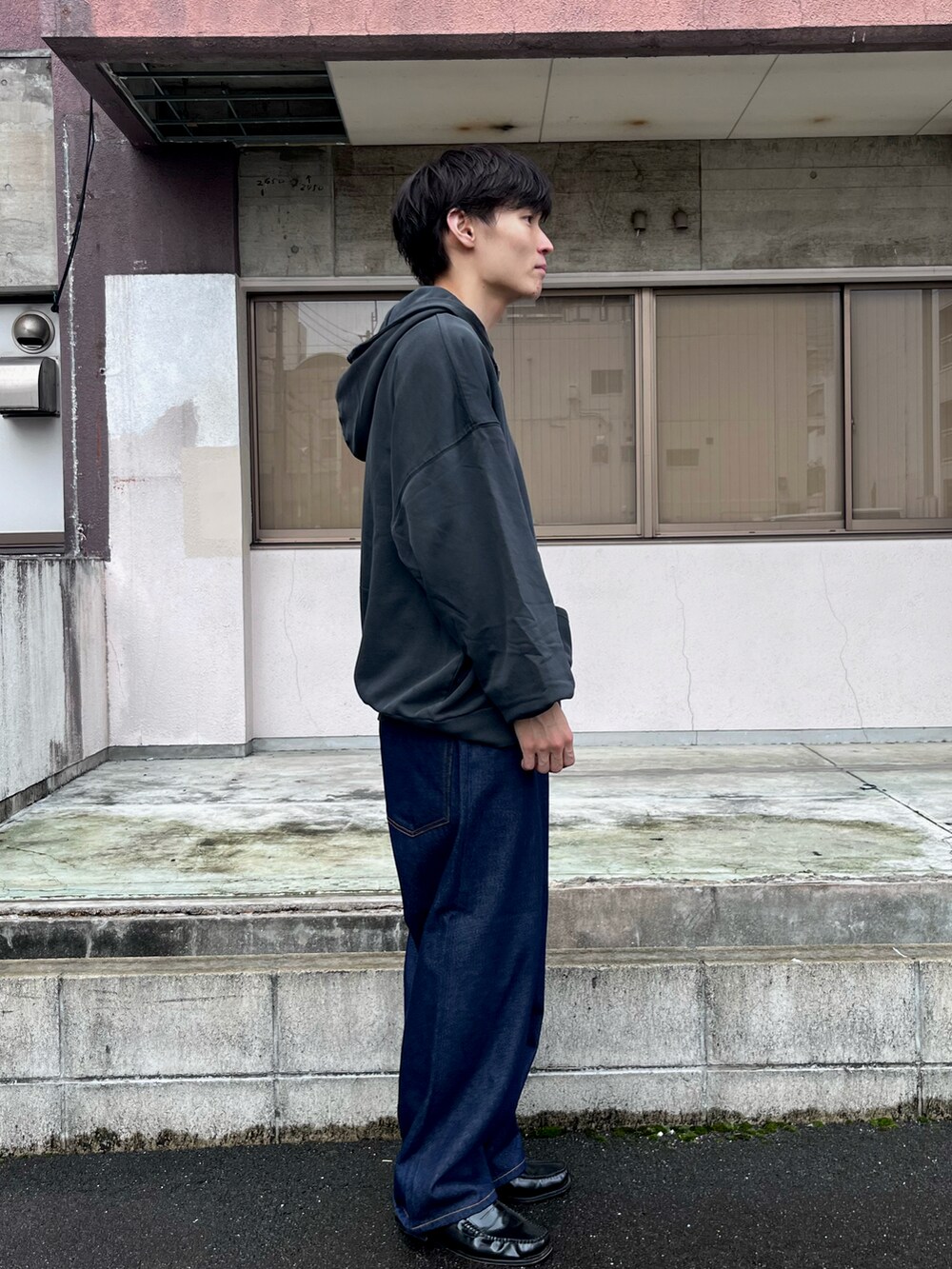 グレー系のパーカー、ブルー系のデニムパンツ、ブラック系のローファーを着用したメンズの秋コーディネートの2枚目の写真