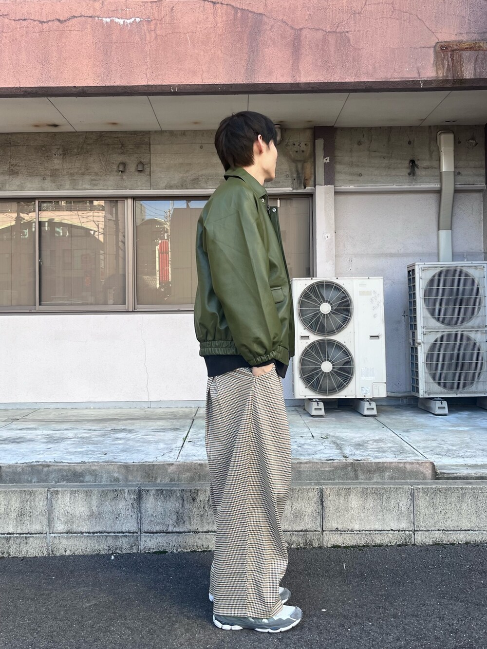 グリーン系のブルゾン、ブラック系のTシャツ/カットソー、ホワイト系のスラックスを着用したメンズの秋コーディネートの2枚目の写真