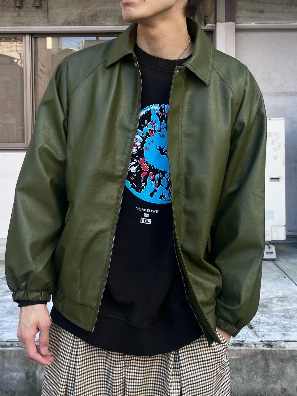 グリーン系のブルゾン、ブラック系のTシャツ/カットソー、ホワイト系のスラックスを着用したメンズの秋コーディネートの3枚目の写真