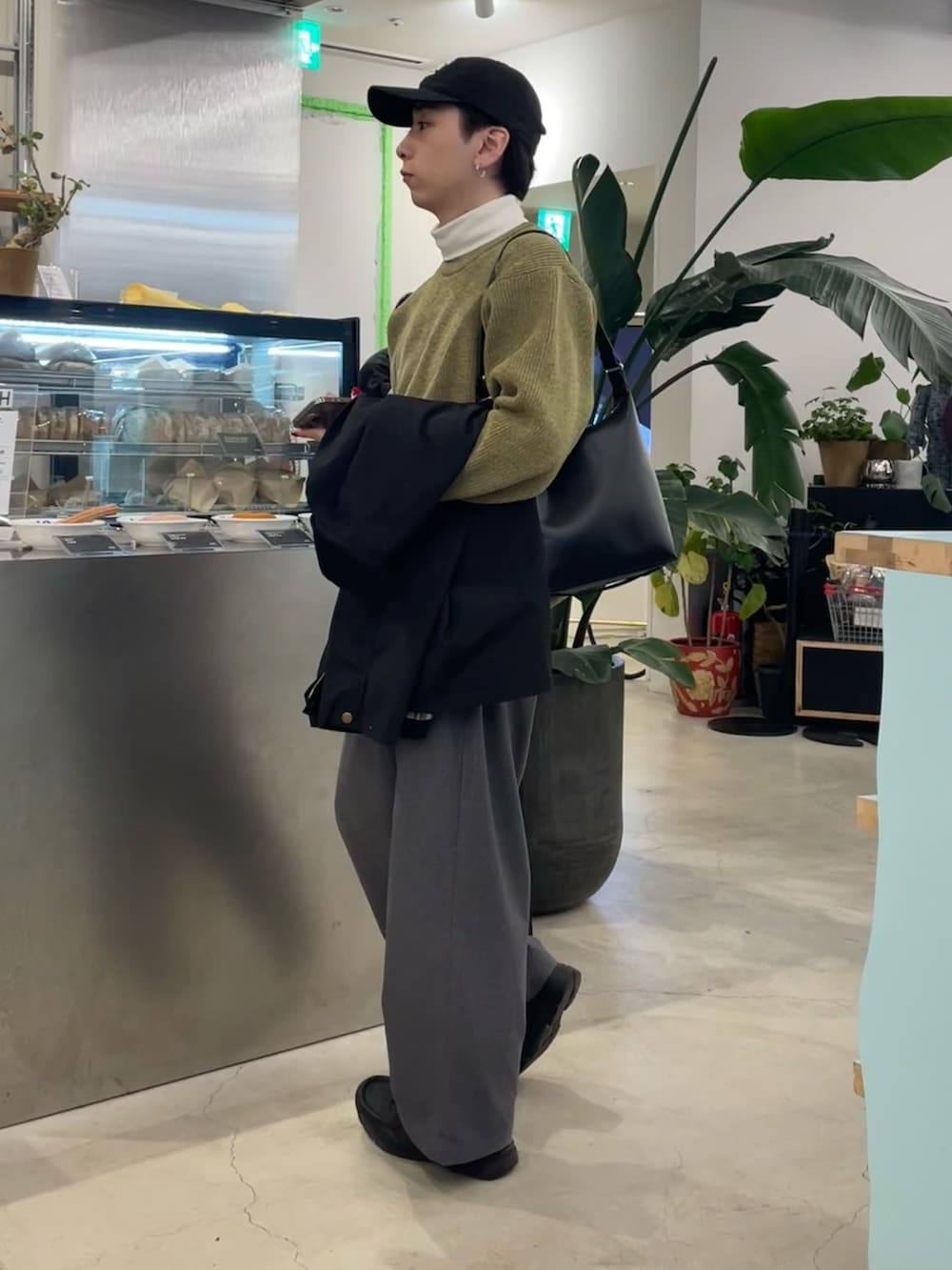 グレー系のスラックス、イエロー系のニット/セーター、ブラック系のブルゾンを着用したメンズの冬コーディネートの3枚目の写真