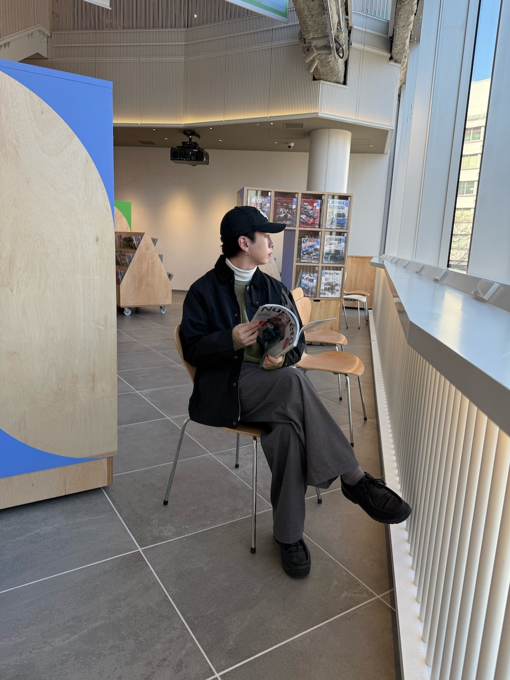 グレー系のスラックス、イエロー系のニット/セーター、ブラック系のブルゾンを着用したメンズの冬コーディネートの2枚目の写真