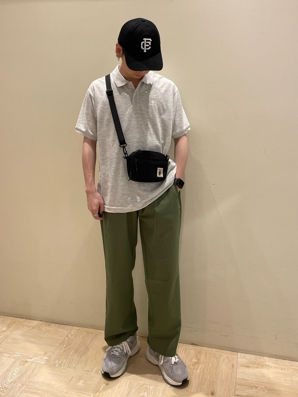 グレー系のポロシャツ、グリーン系のその他パンツ、ブラック系のキャップを着用したメンズの夏コーディネートの2枚目の写真