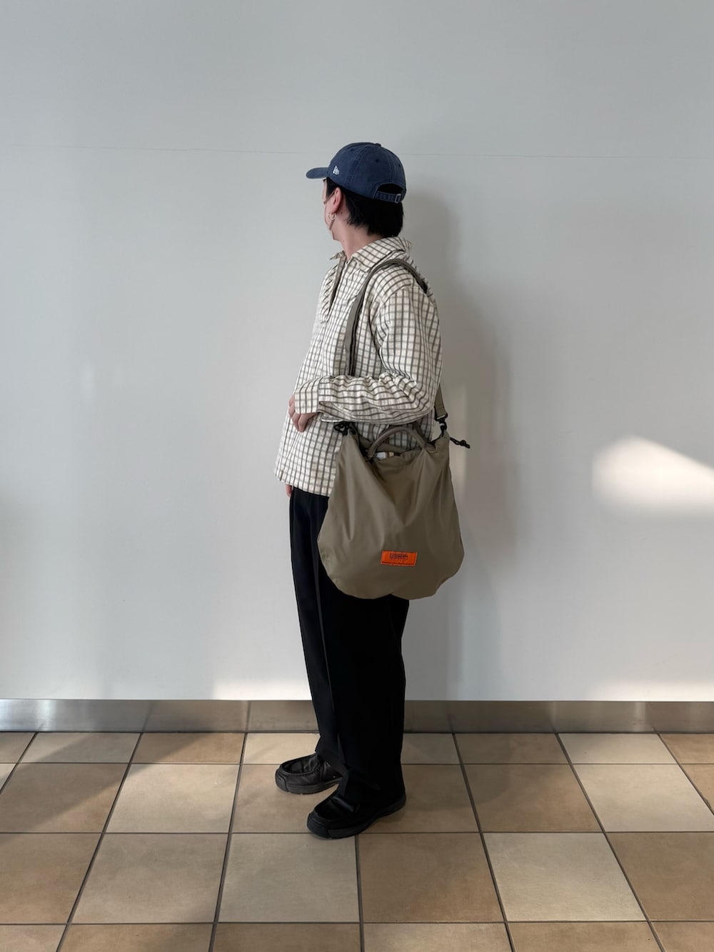 ホワイト系のブルゾン、ベージュ系のショルダーバッグ、ブラック系のその他パンツを着用したメンズの春コーディネートの6枚目の写真