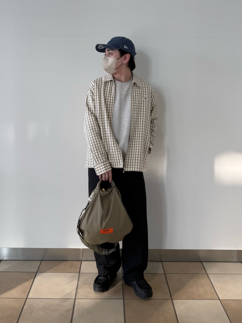 ホワイト系のブルゾン、ベージュ系のショルダーバッグ、ブラック系のその他パンツを着用したメンズの春コーディネートの2枚目の写真