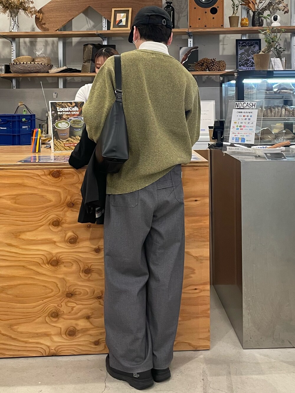 グレー系のスラックス、イエロー系のニット/セーター、ブラック系のブルゾンを着用したメンズの冬コーディネートの5枚目の写真