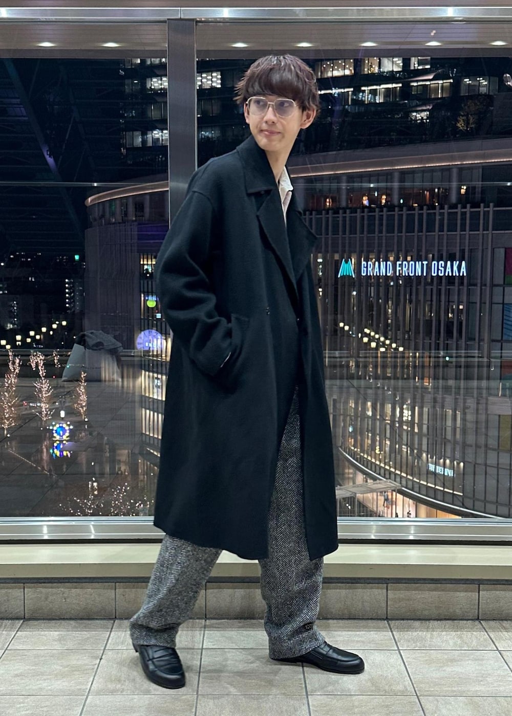 ブラック系のその他パンツ、ブラック系のステンカラーコート、ピンク系のポロシャツを着用したメンズの冬コーディネートの6枚目の写真