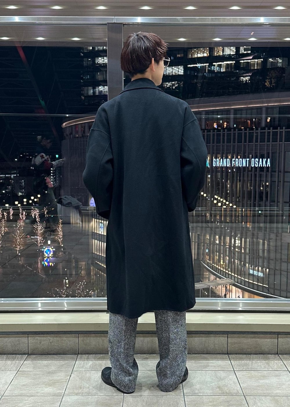 ブラック系のその他パンツ、ブラック系のステンカラーコート、ピンク系のポロシャツを着用したメンズの冬コーディネートの4枚目の写真