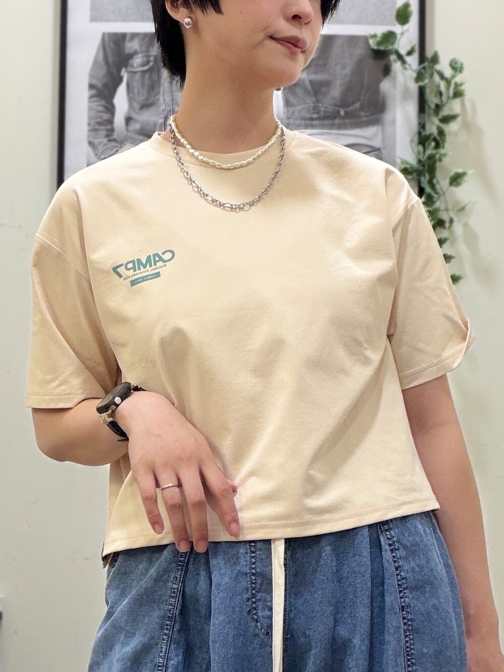 ベージュ系のTシャツ/カットソー、ホワイト系のベスト、ブルー系のデニムパンツを着用したレディースの春コーディネートの4枚目の写真