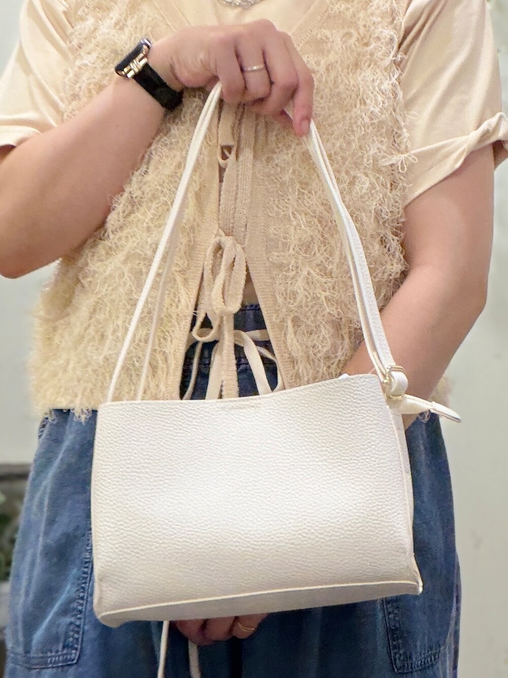 ベージュ系のTシャツ/カットソー、ホワイト系のベスト、ブルー系のデニムパンツを着用したレディースの春コーディネートの9枚目の写真