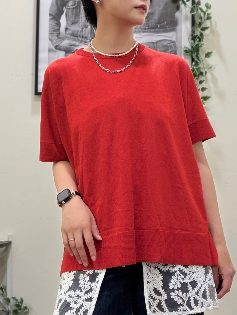 ブルー系のデニムパンツ、レッド系のニット/セーター、ホワイト系のスカートを着用したレディースの春コーディネートの4枚目の写真