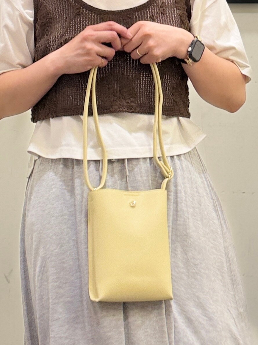 イエロー系のショルダーバッグ、グレー系のスカート、ブラウン系のベストを着用したレディースの春コーディネートの7枚目の写真