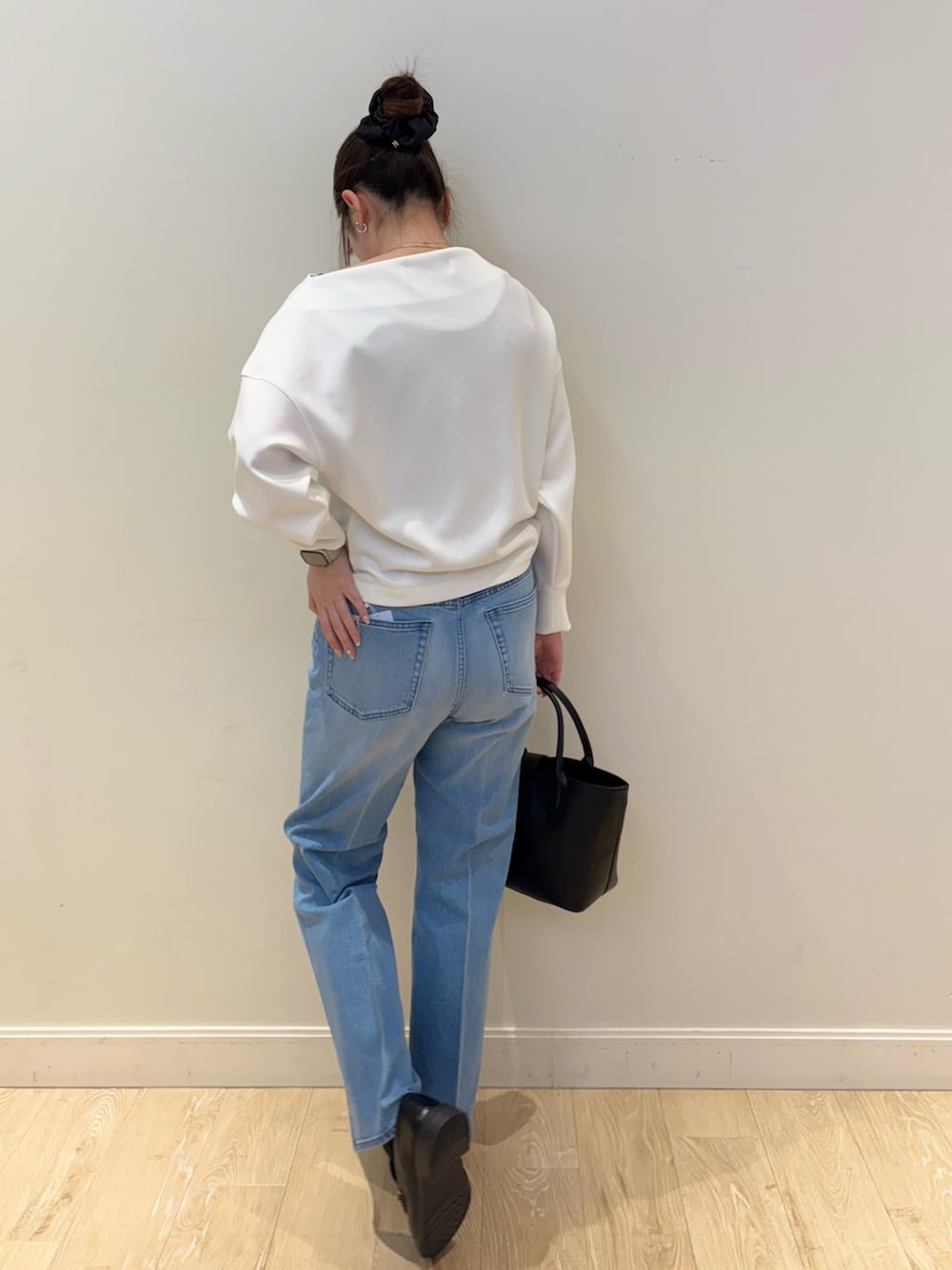 ブラック系のトートバッグ、ブルー系のデニムパンツ、ホワイト系のTシャツ/カットソーを着用したレディースの冬コーディネートの2枚目の写真