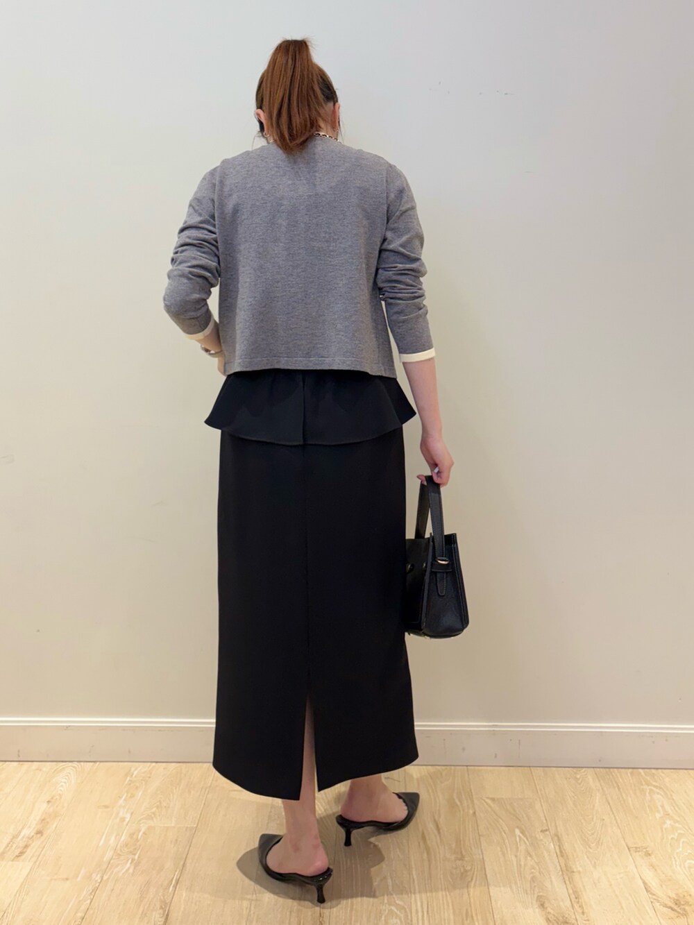 ブラック系のショルダーバッグ、ブラック系のスカート、ホワイト系のタンクトップを着用したレディースの秋コーディネートの2枚目の写真