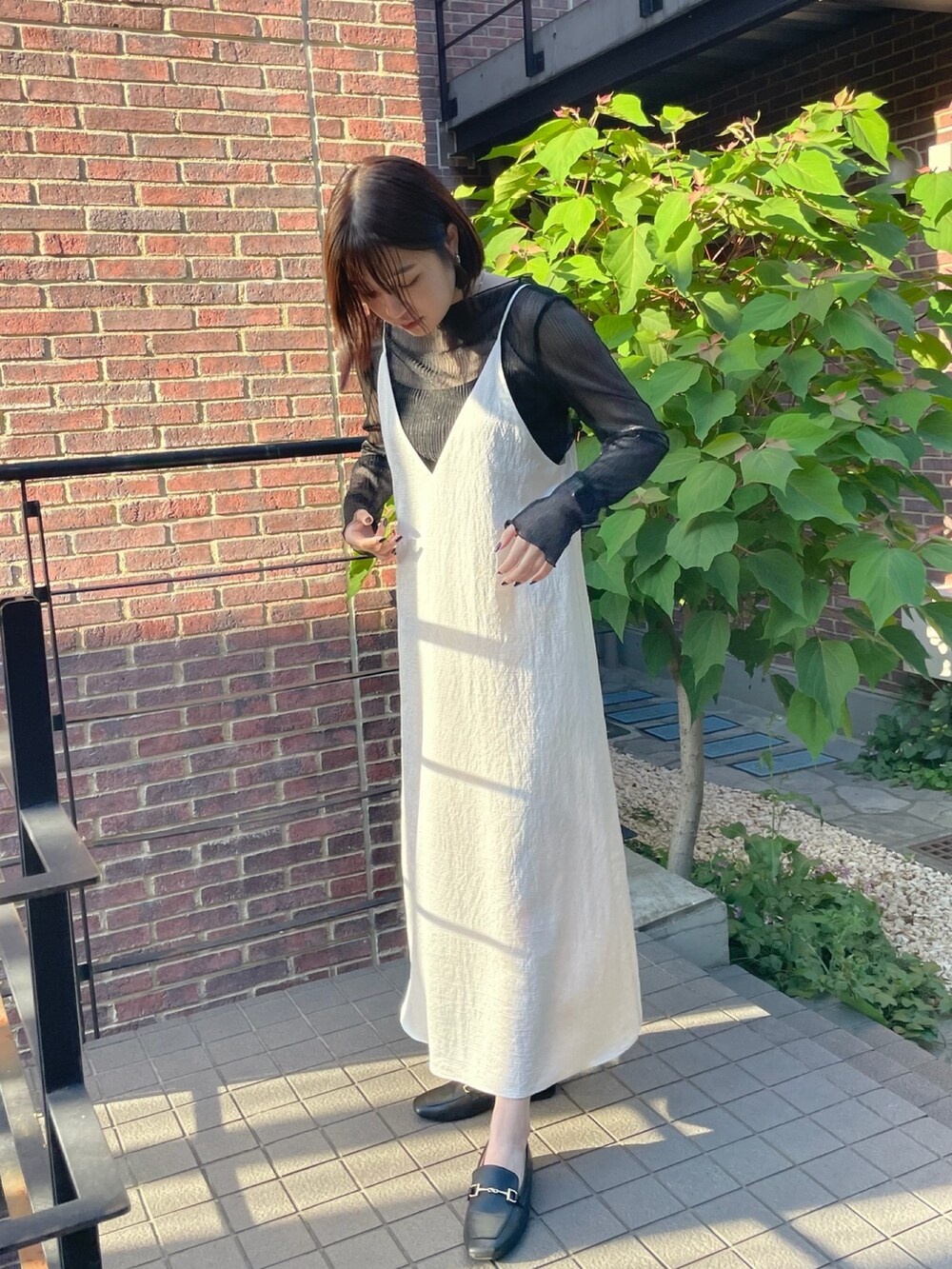 ホワイト系のワンピース、ブラック系のTシャツ/カットソーを着用したレディースの夏コーディネートの2枚目の写真