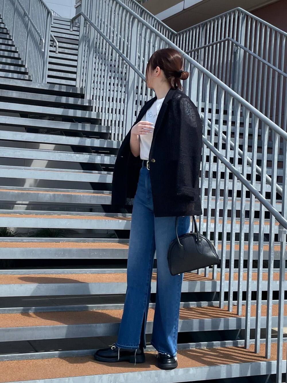 ホワイト系のTシャツ/カットソー、ブラック系のボストンバッグ、ブルー系のデニムパンツを着用したレディースの春コーディネートの4枚目の写真