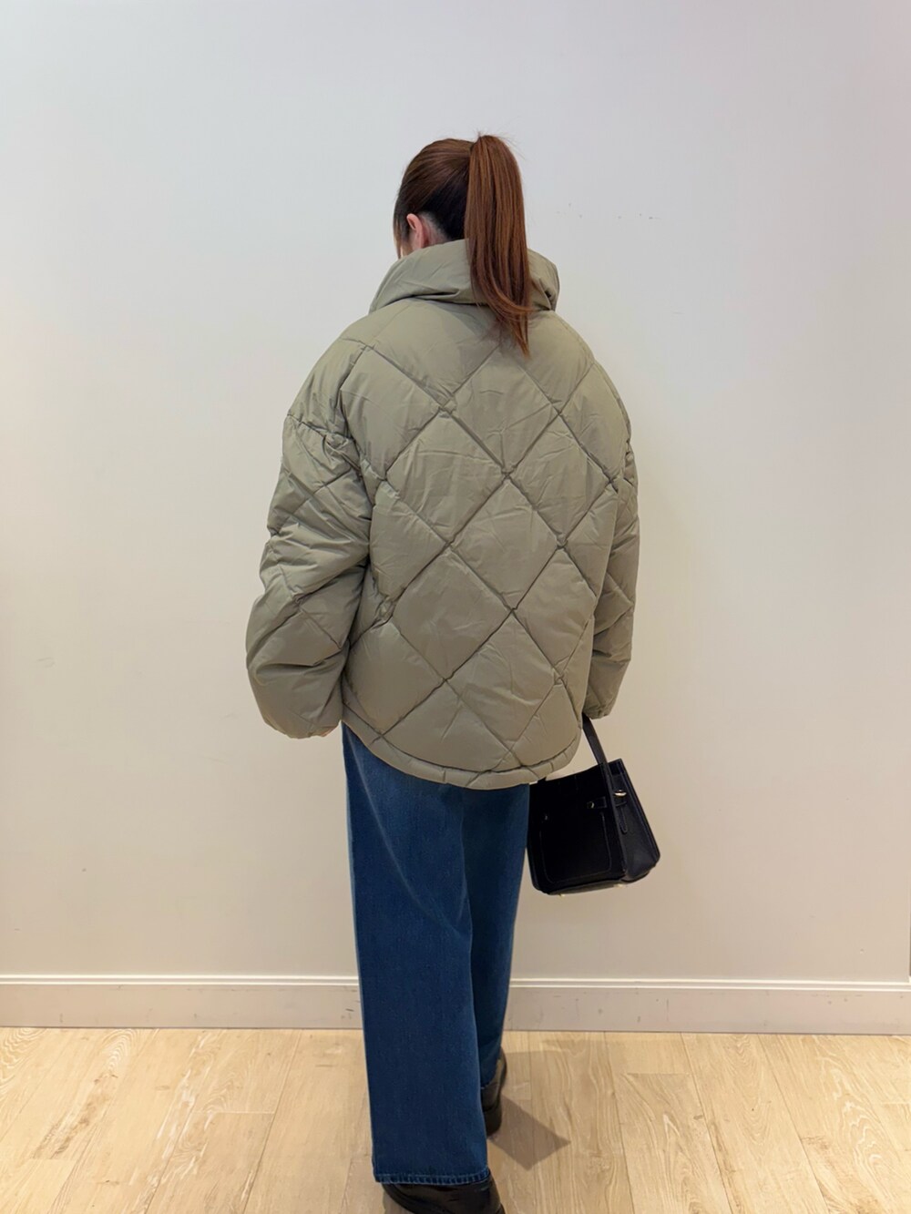 イエロー系のニット/セーター、ブラック系のショルダーバッグ、ブルー系のデニムパンツを着用したレディースの秋コーディネートの3枚目の写真