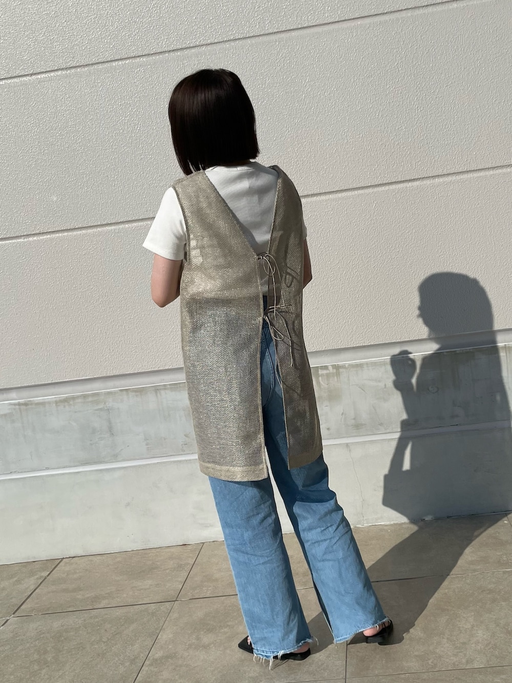 ブルー系のデニムパンツ、ブラック系のショルダーバッグ、ベージュ系のブルゾンを着用したレディースの夏コーディネートの3枚目の写真