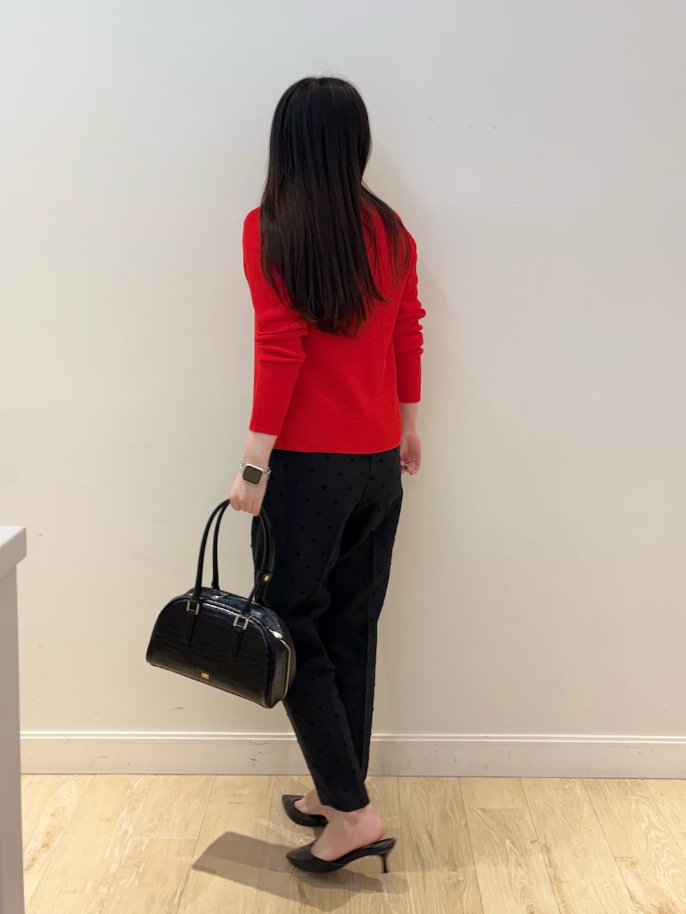 ブラック系のボストンバッグ、ブラック系のその他パンツ、レッド系のカーディガン/ボレロを着用したレディースの秋コーディネートの4枚目の写真