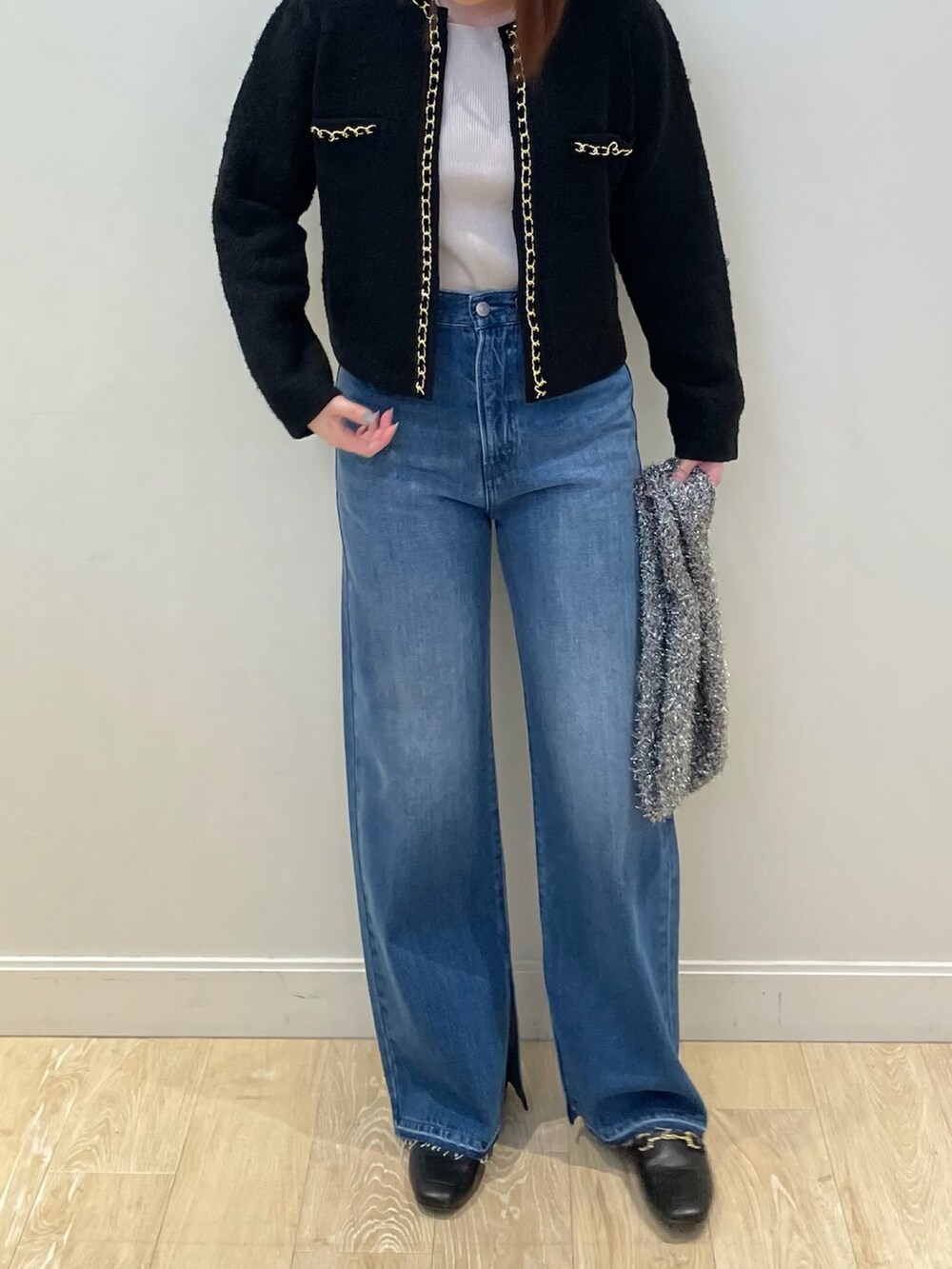 ブルー系のデニムパンツ、ゴールド系のニット/セーター、ブラック系のカーディガン/ボレロを着用したレディースの秋コーディネートの3枚目の写真