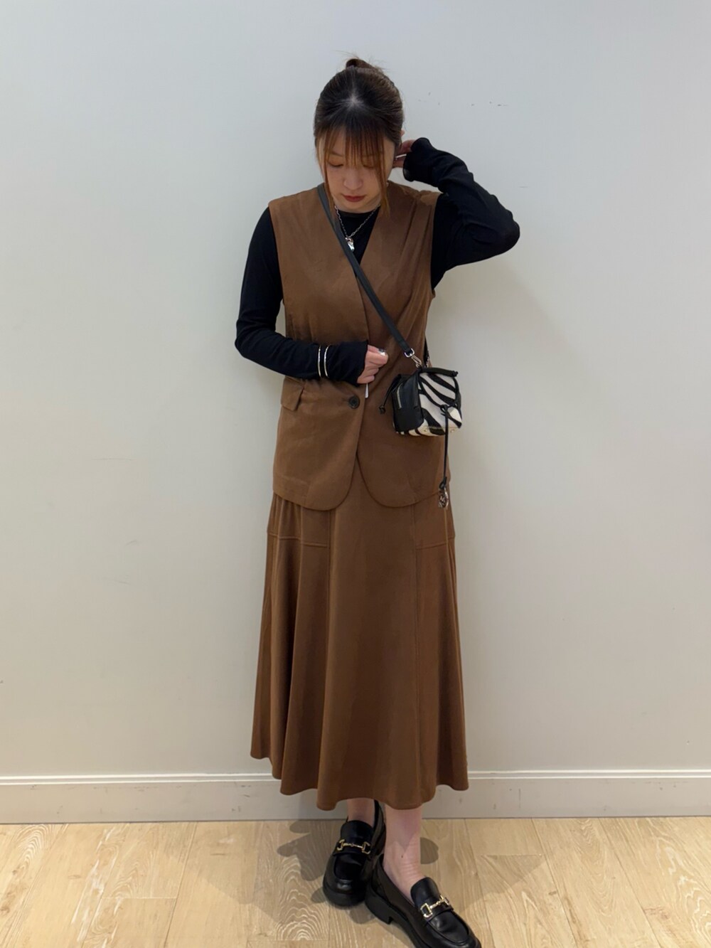 ブラウン系のスカート、その他のショルダーバッグ、ブラウン系のベストを着用したレディースの秋コーディネートの4枚目の写真