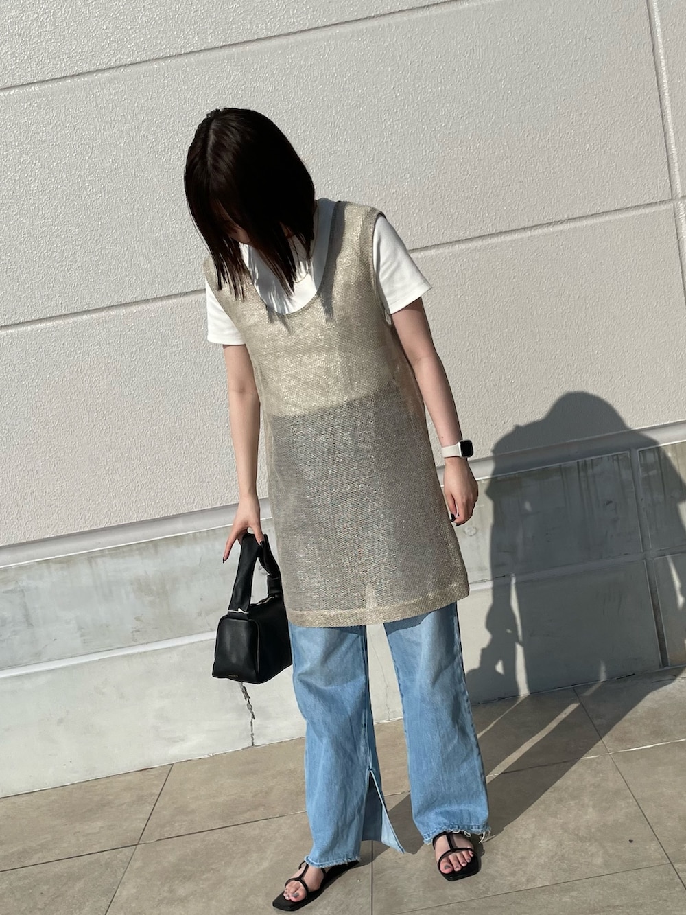 ブルー系のデニムパンツ、ブラック系のショルダーバッグ、ベージュ系のブルゾンを着用したレディースの夏コーディネートの4枚目の写真