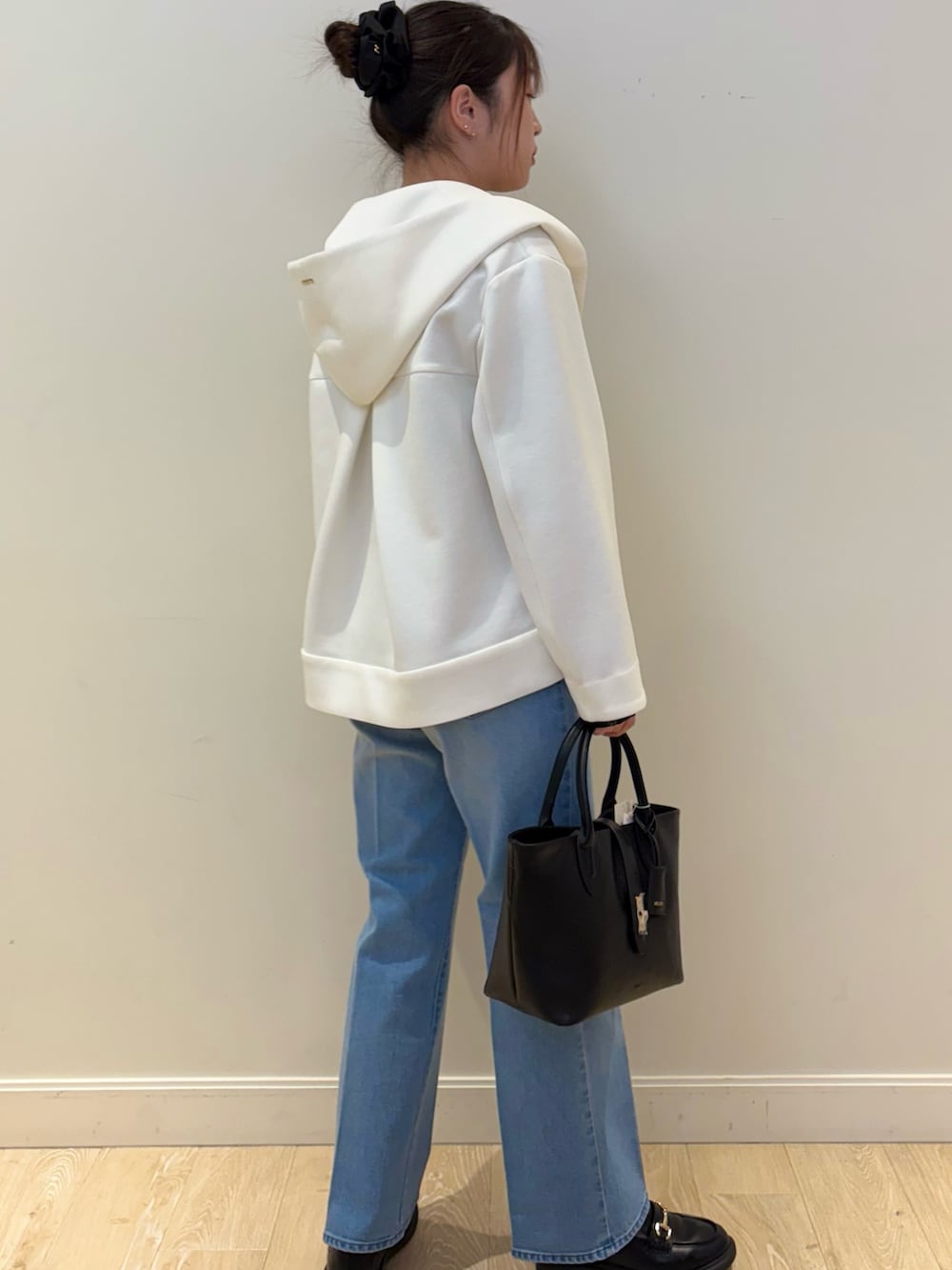 ブラック系のトートバッグ、ブルー系のデニムパンツ、ホワイト系のブルゾンを着用したレディースの冬コーディネートの3枚目の写真