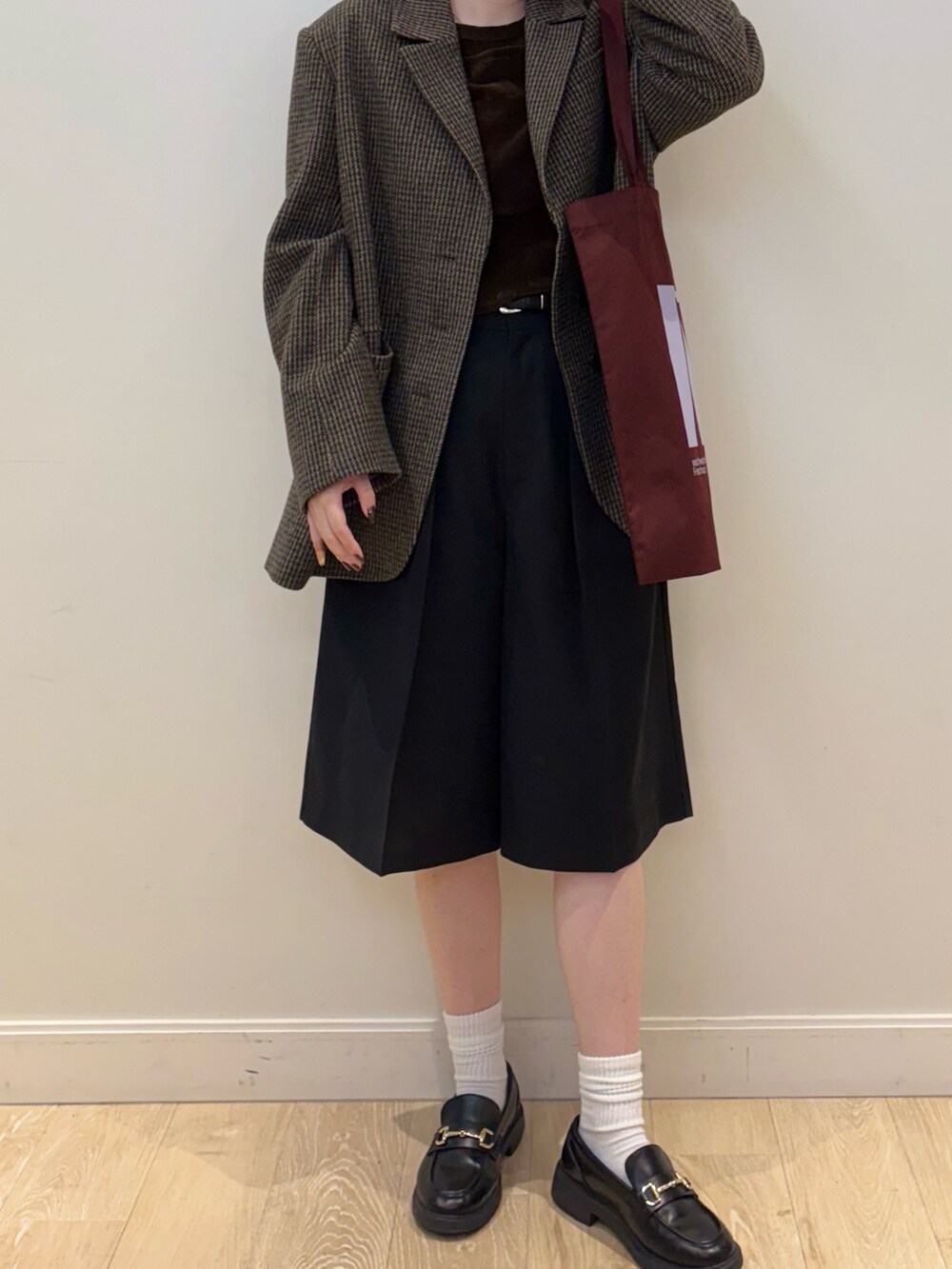 レッド系のトートバッグ、ブラック系のその他パンツ、ブラウン系のTシャツ/カットソーを着用したレディースの秋コーディネートの2枚目の写真