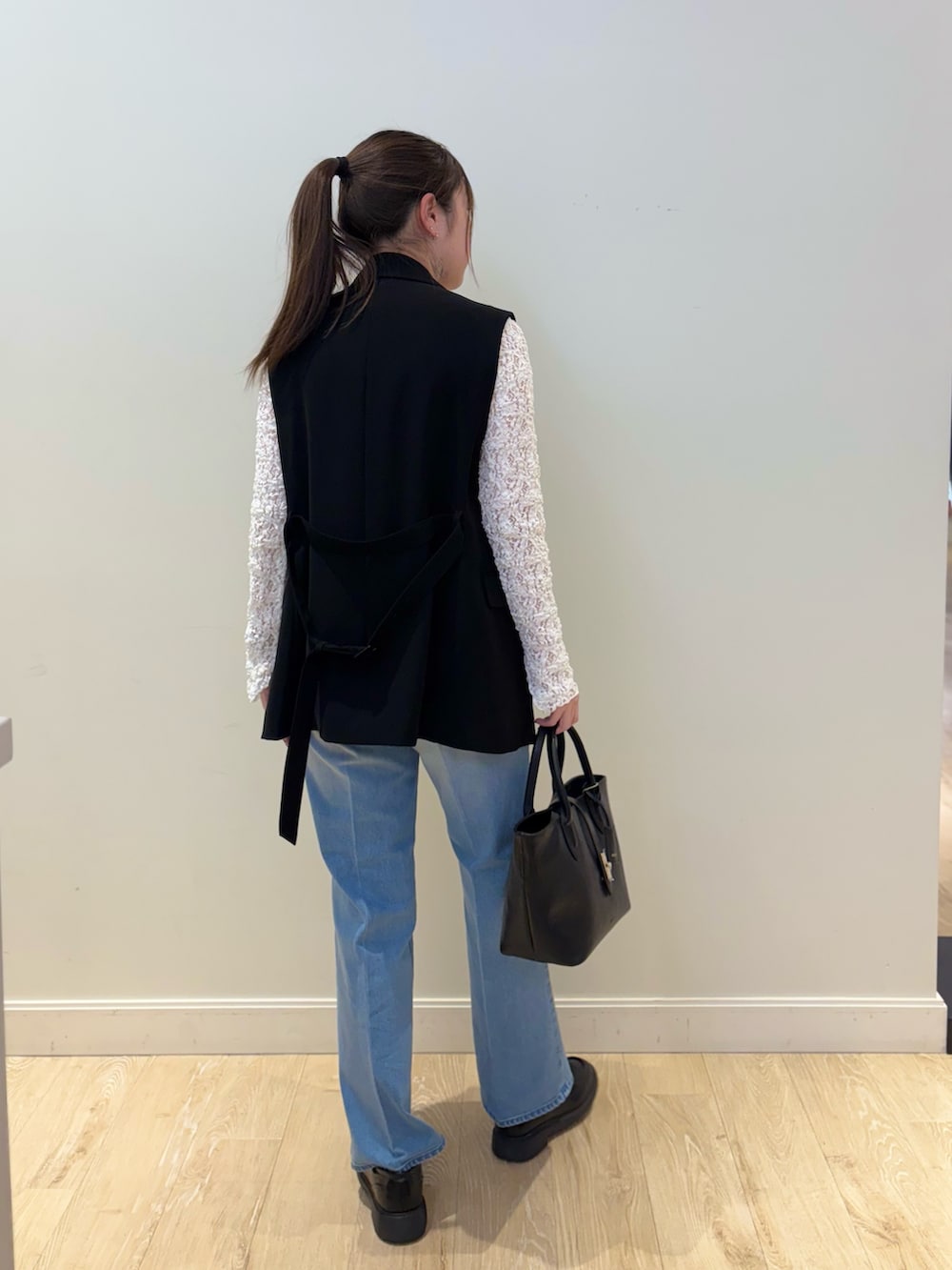 ブラック系のトートバッグ、ブルー系のデニムパンツ、ホワイト系のカーディガン/ボレロを着用したレディースの冬コーディネートの2枚目の写真