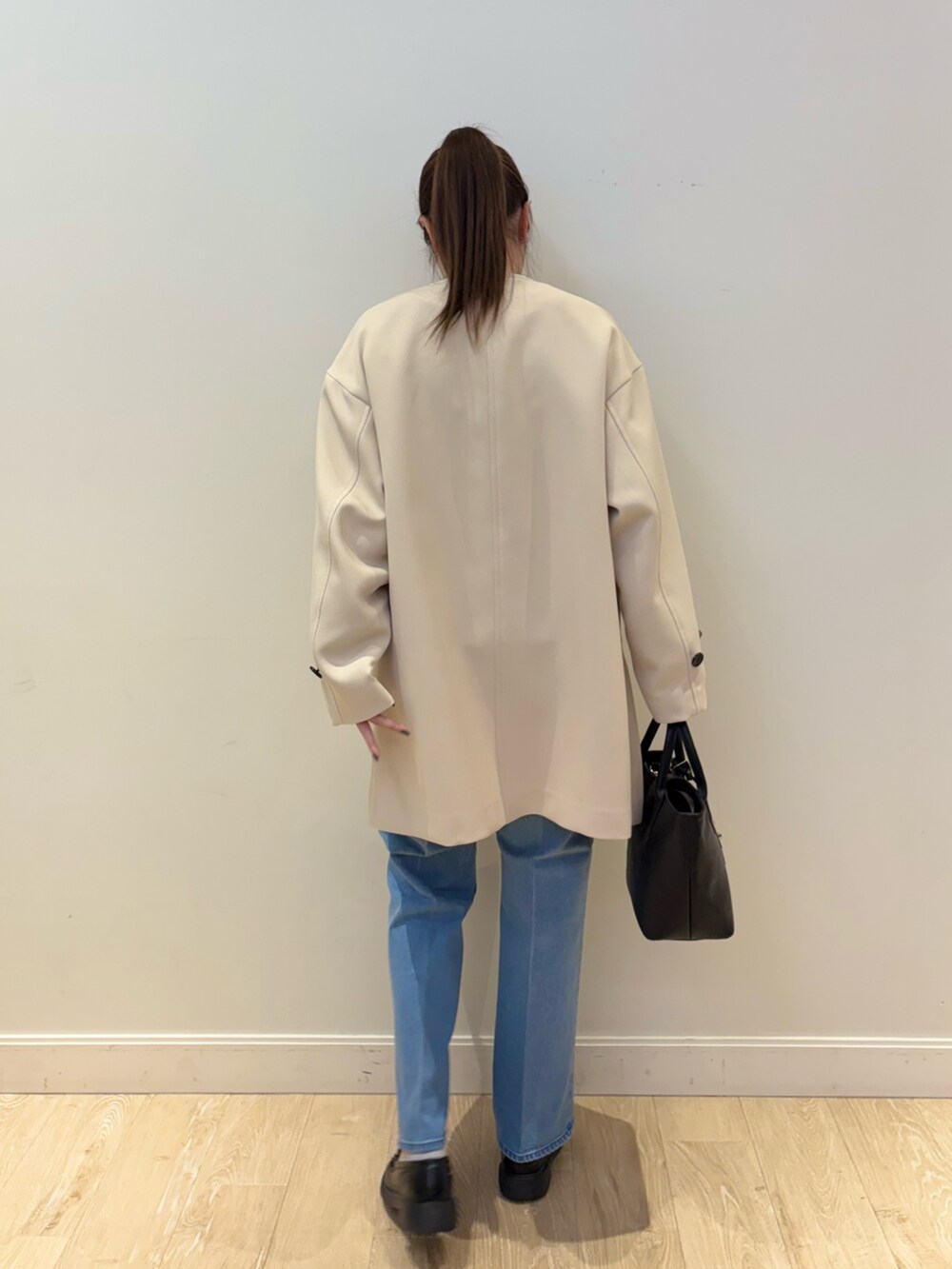 ブラック系のトートバッグ、ブルー系のデニムパンツ、ブラック系のニット/セーターを着用したレディースの冬コーディネートの7枚目の写真