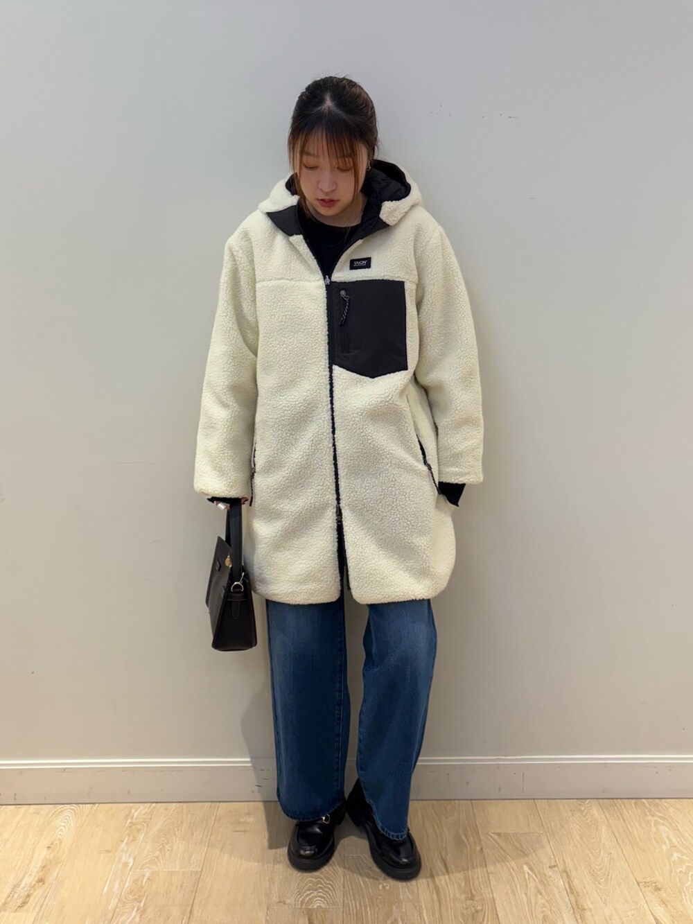 ブラック系のショルダーバッグ、ブルー系のデニムパンツ、ブラック系のTシャツ/カットソーを着用したレディースの秋コーディネートの4枚目の写真