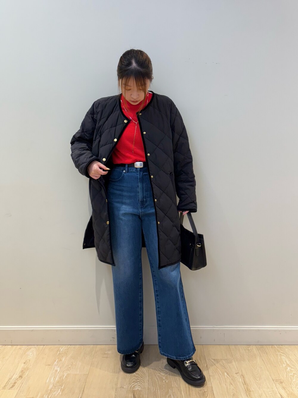 ブルー系のデニムパンツ、ブラック系のショルダーバッグ、レッド系のニット/セーターを着用したレディースの秋コーディネートの2枚目の写真