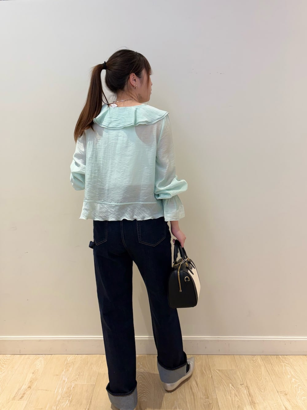 ホワイト系のタンクトップ、ブラック系のボストンバッグ、ブルー系のデニムパンツを着用したレディースの春コーディネートの3枚目の写真