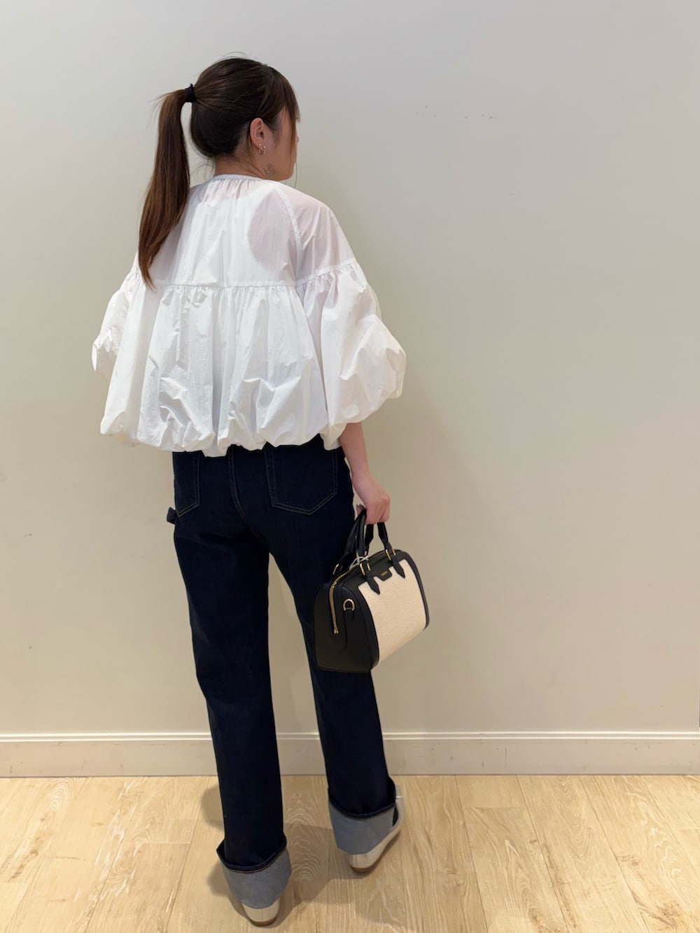 ブルー系のデニムパンツ、ブラック系のボストンバッグ、ホワイト系のブルゾンを着用したレディースの春コーディネートの2枚目の写真