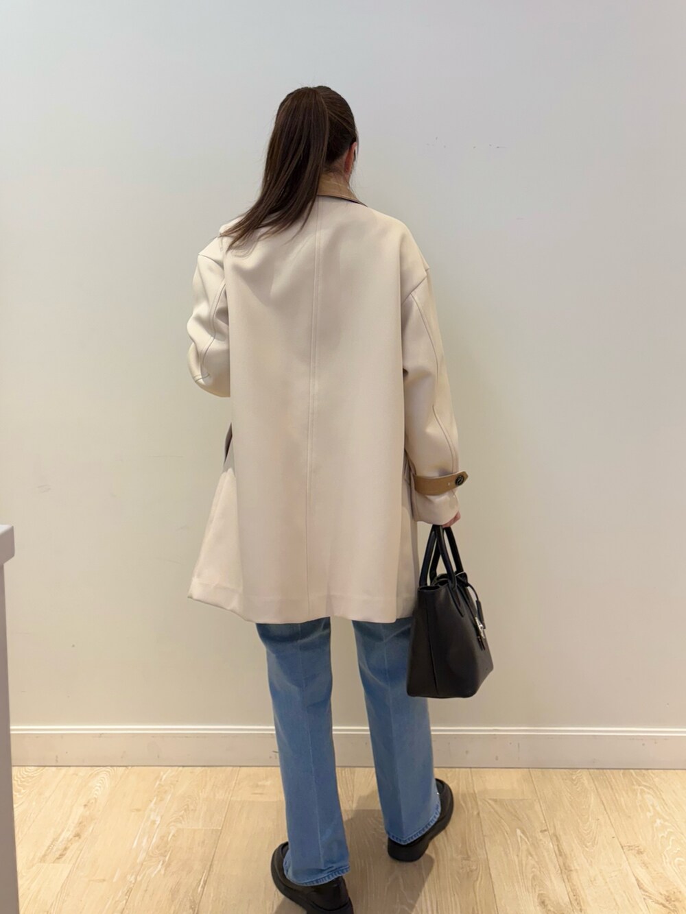 ブラック系のトートバッグ、ブルー系のデニムパンツ、ブラック系のニット/セーターを着用したレディースの冬コーディネートの5枚目の写真