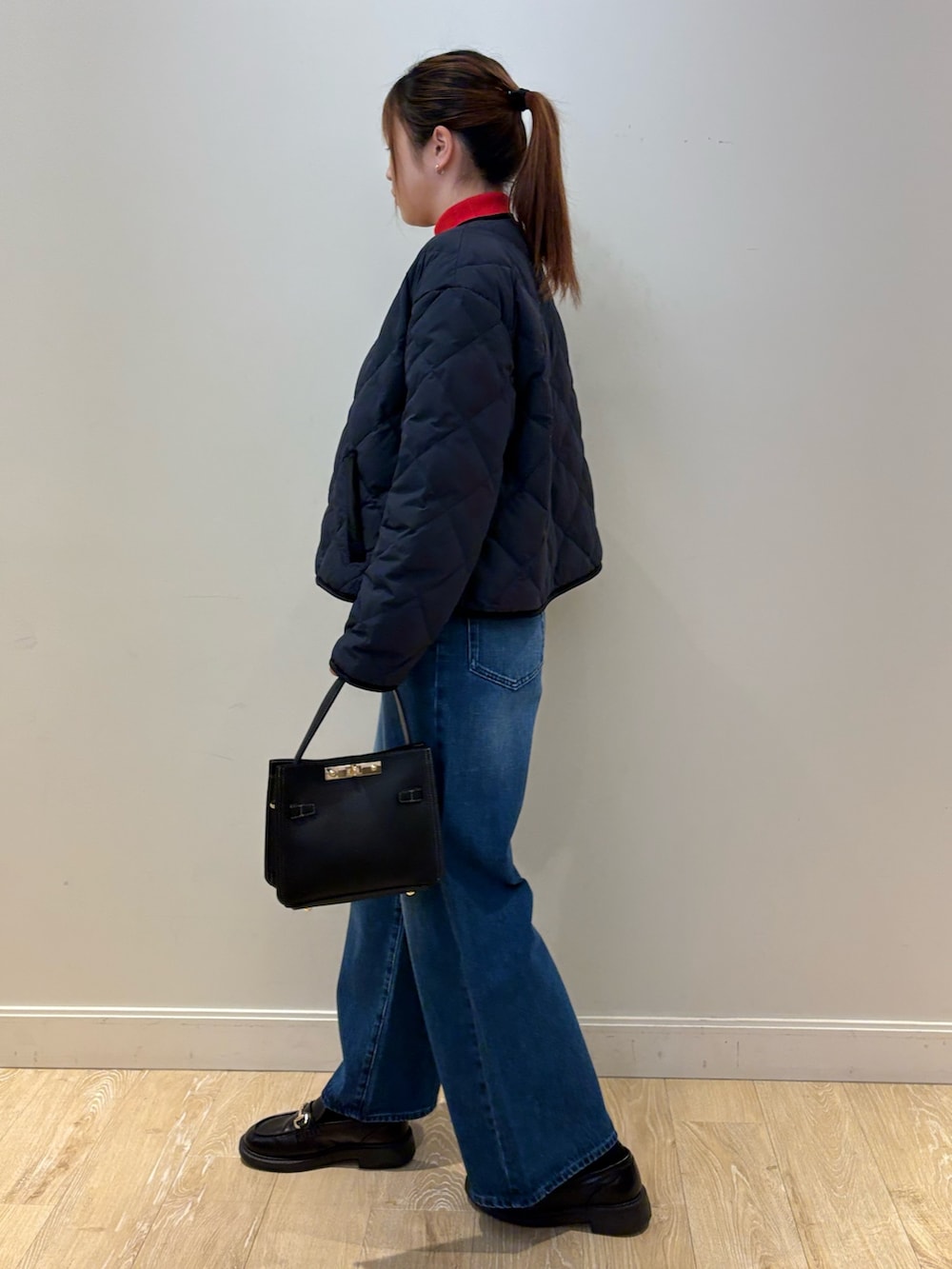 ブルー系のデニムパンツ、ブラック系のショルダーバッグ、レッド系のニット/セーターを着用したレディースの秋コーディネートの2枚目の写真