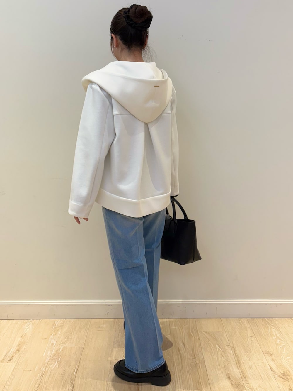 ブラック系のトートバッグ、ブルー系のデニムパンツ、ホワイト系のブルゾンを着用したレディースの冬コーディネートの2枚目の写真