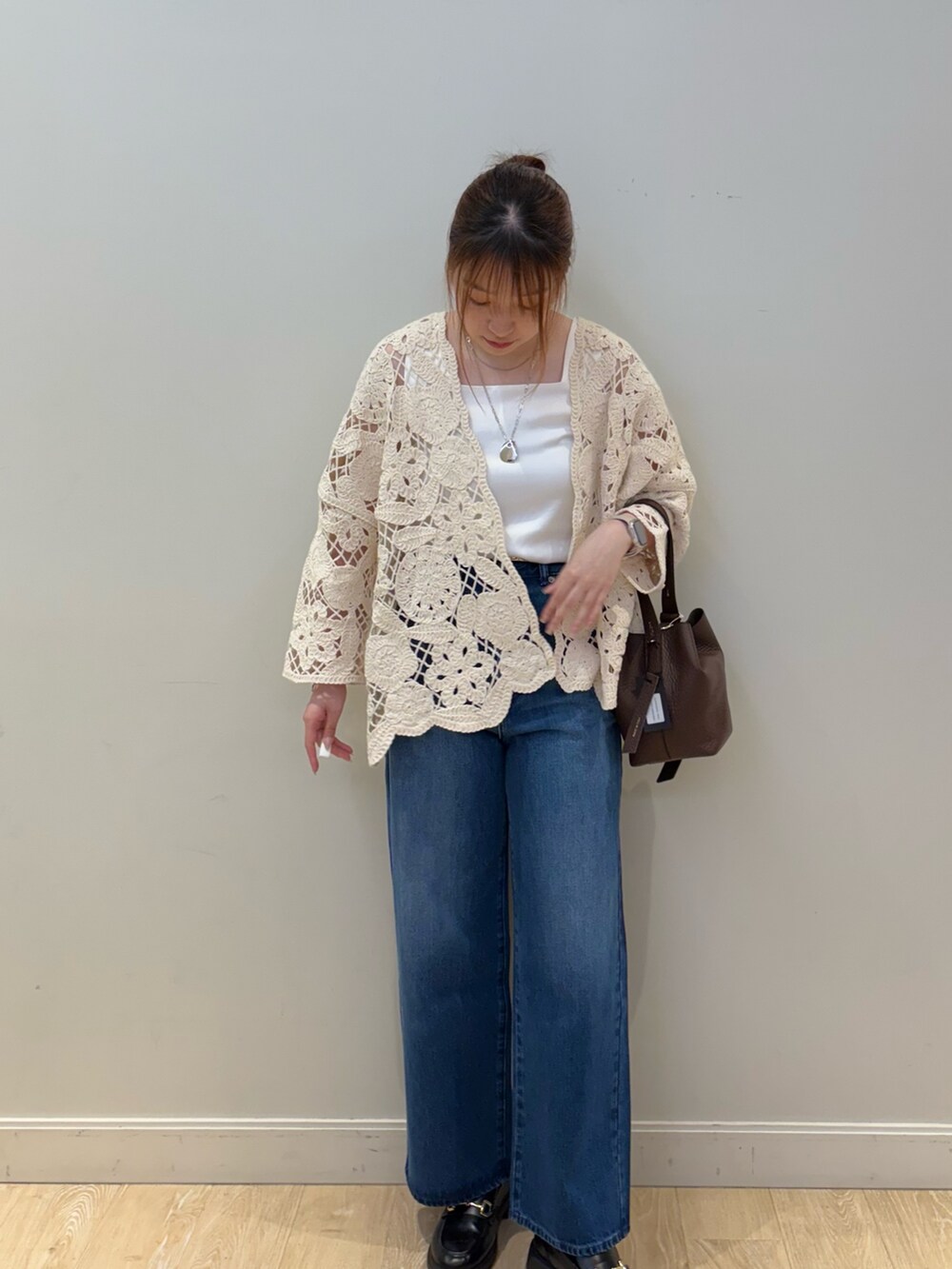 ブルー系のデニムパンツ、ブラウン系のショルダーバッグ、ホワイト系のタンクトップを着用したレディースの夏コーディネートの3枚目の写真