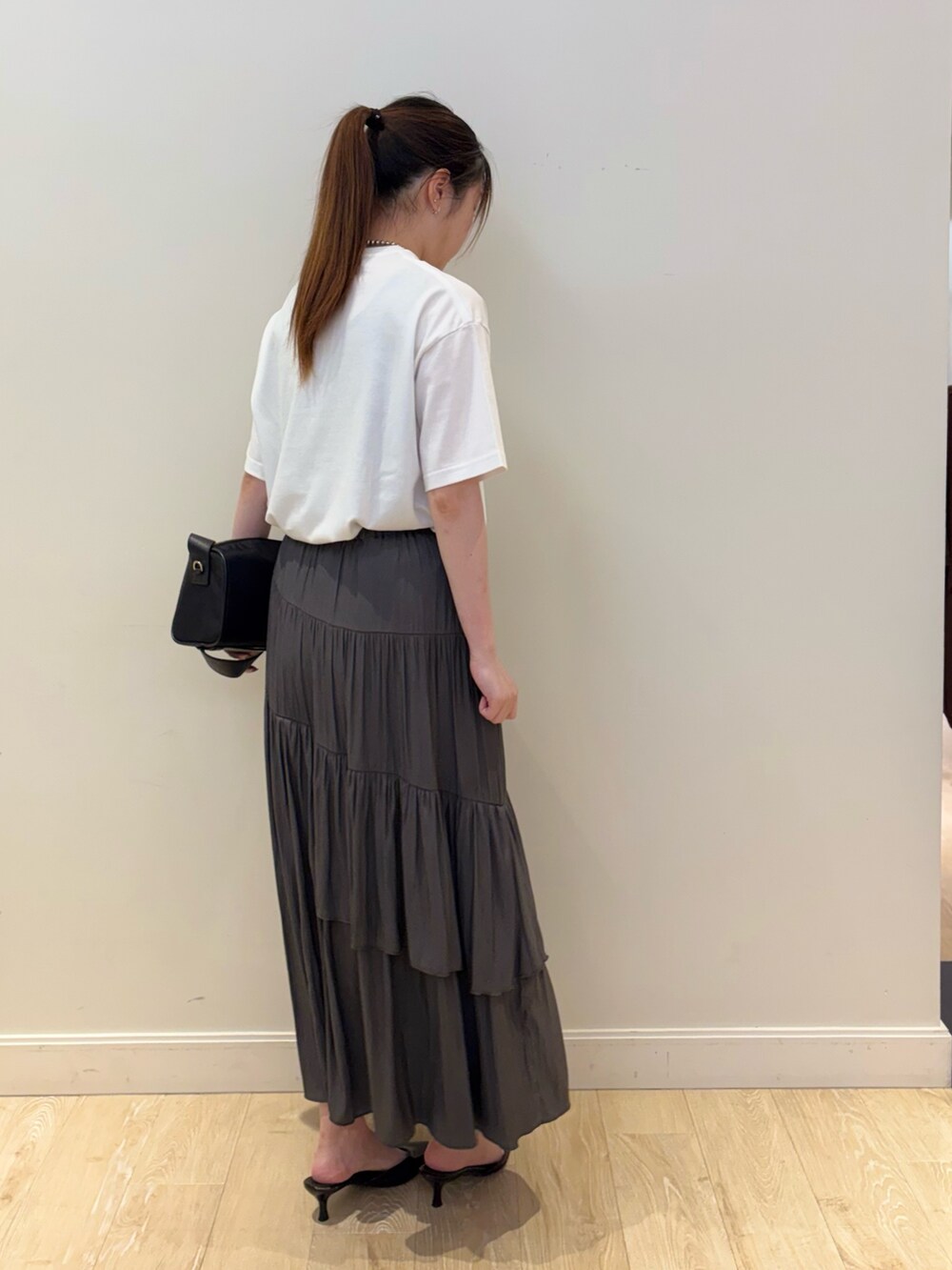 ブラック系のショルダーバッグ、グレー系のスカート、ホワイト系のTシャツ/カットソーを着用したレディースの夏コーディネートの4枚目の写真
