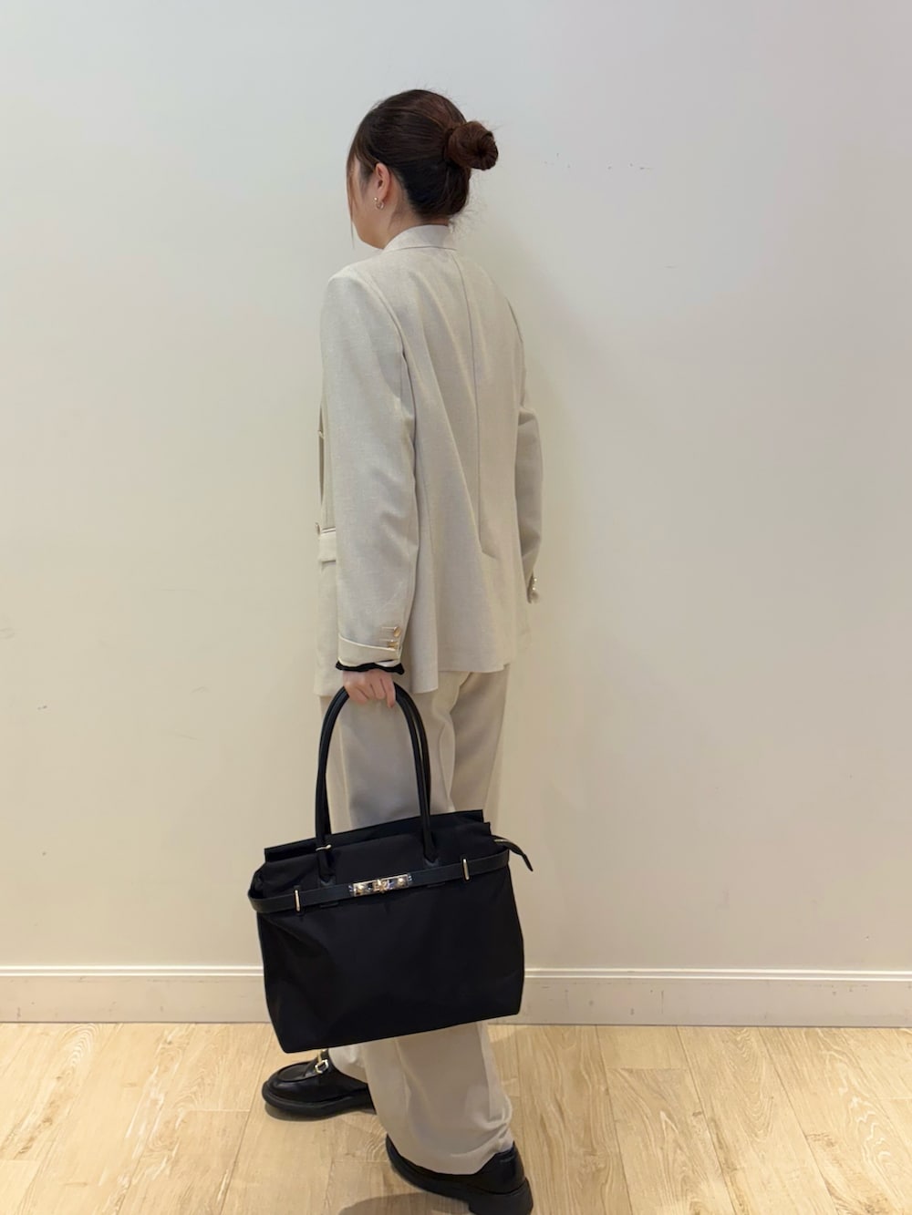 ブラック系のトートバッグ、ブラック系のTシャツ/カットソー、ベージュ系のテーラードジャケットを着用したレディースの春コーディネートの2枚目の写真
