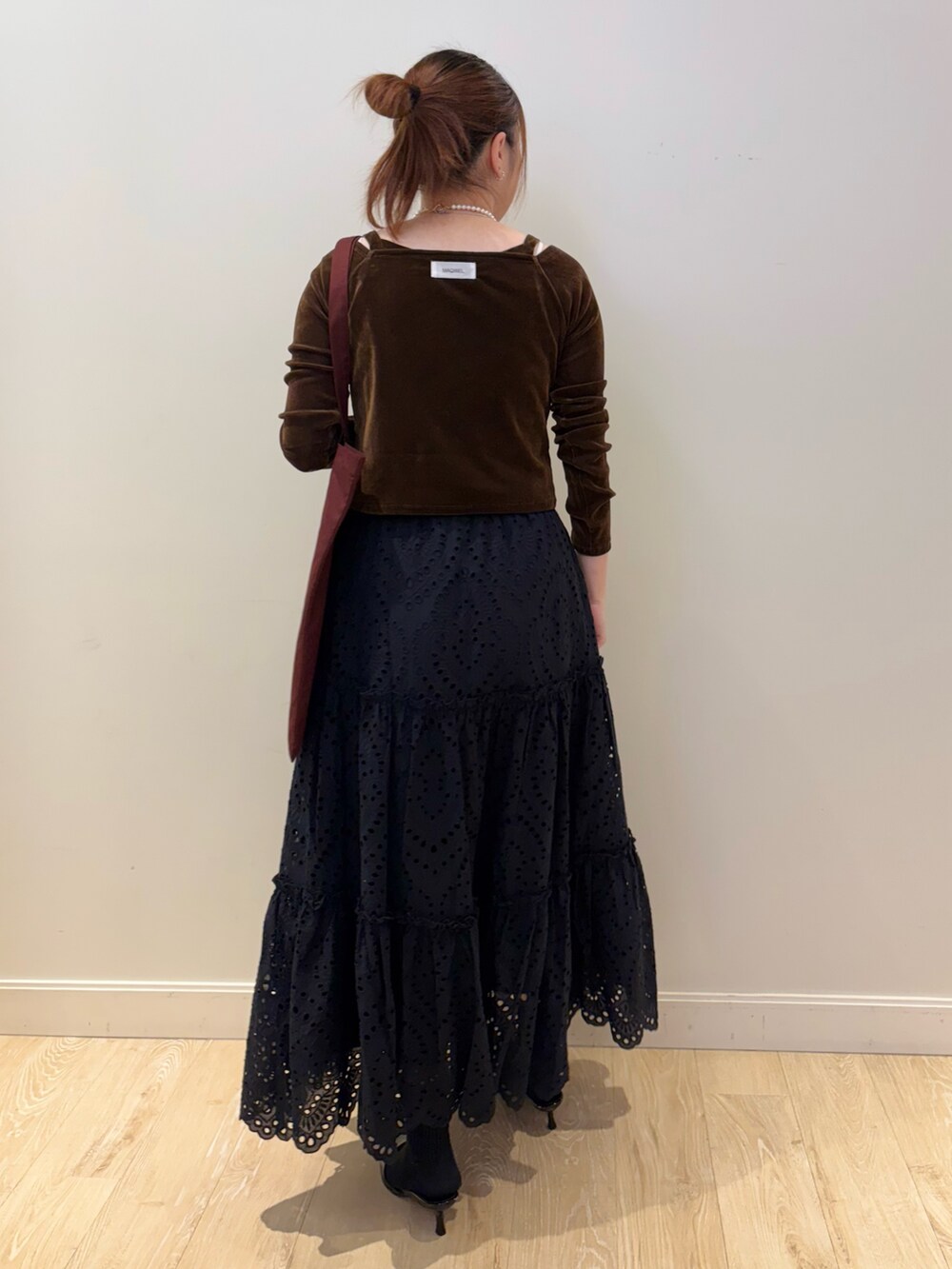 ブラック系のスカート、レッド系のトートバッグ、ブラウン系のTシャツ/カットソーを着用したレディースの秋コーディネートの2枚目の写真