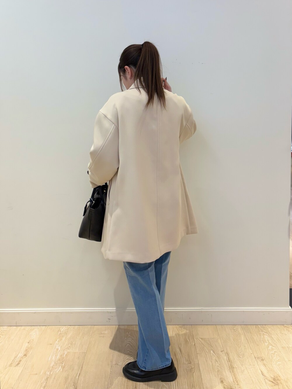 ブラック系のトートバッグ、ブルー系のデニムパンツ、ブラック系のニット/セーターを着用したレディースの冬コーディネートの2枚目の写真