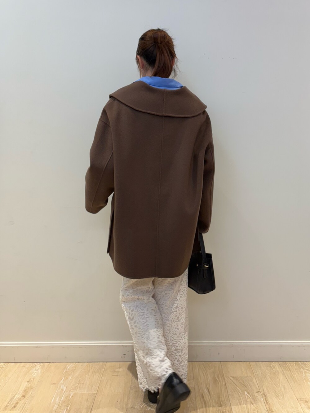 ブラック系のショルダーバッグ、ブラウン系のその他アウター、ブルー系のシャツ/ブラウスを着用したレディースの冬コーディネートの2枚目の写真