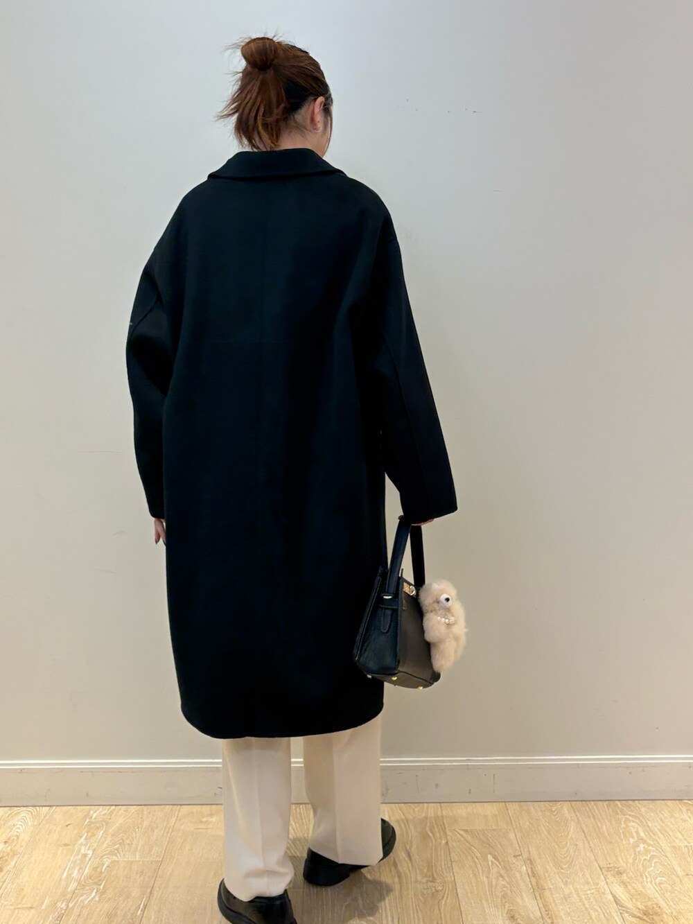 ブラック系のニット/セーター、ブラック系のショルダーバッグ、ホワイト系のその他パンツを着用したレディースの秋コーディネートの2枚目の写真